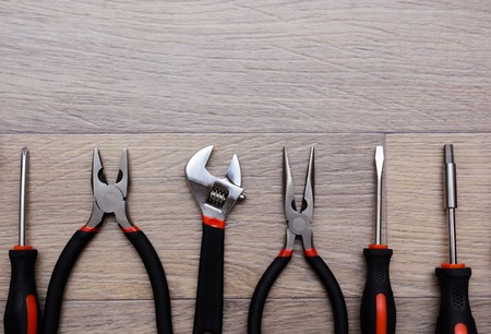 set with tool on a wooden table. screwdriver, gayachnye wrenches, pliers, wire cutters. Top view.