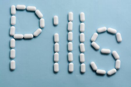 white pills on blue sky background. Word - pillsの写真素材