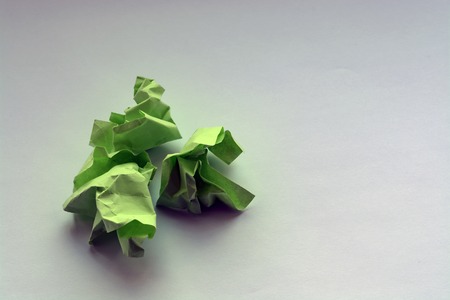 wrinkled green paper on a white table. crumpled notes of failed sketches, close-up