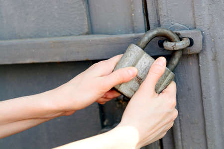 female hands pulled the gray old padlock.の写真素材