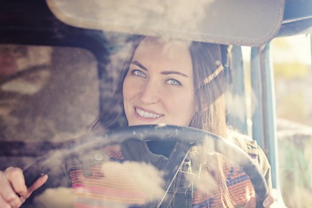woman truck driver in the car. Girl smiling at camera and holding the steering wheel.