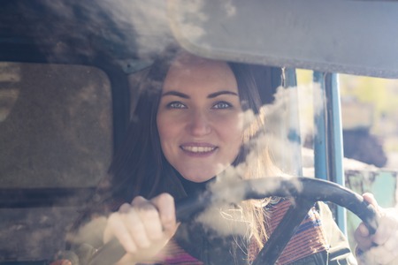 woman truck driver in the car. Girl smiling at camera and holding the steering wheel
