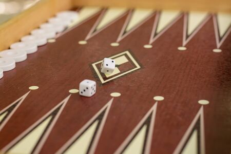 backgammon bone square white dice for gambling with blurred background.