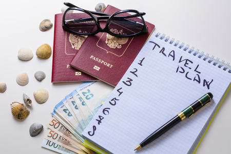 Traveler items on white table. Glasses, passport, euros, Notepad with pen and shell.の写真素材