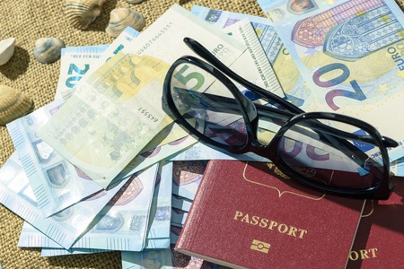 Traveler items on white table. Glasses, passport, euros, Notepad with pen and shell.の写真素材