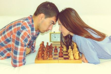 Relaxed young couple playing chess at home lying on sofa.の写真素材