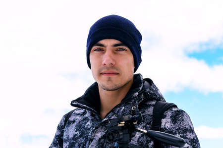 Handsome man in winter clothes against the skyの写真素材