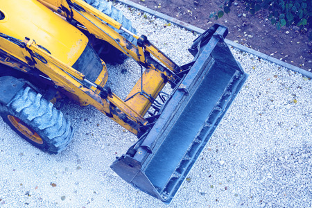 Yellow bulldozer, loading gravel for road construction.