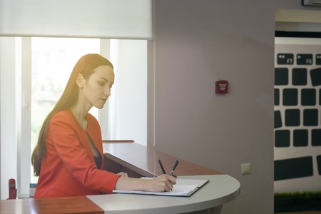 Secretary in a red suit puts a stamp in the incoming messages. office work, document control.の写真素材