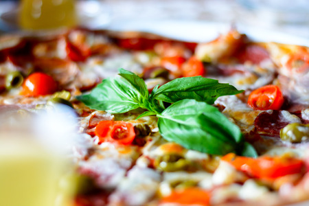 A tasty pizza with vegetables, meat, and sauces on a cafe on a white plate. Close upの写真素材