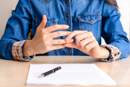Concept Of Divorce.Young woman in a jeans shirt signed divorce settlement and takes off his wedding ringの写真素材