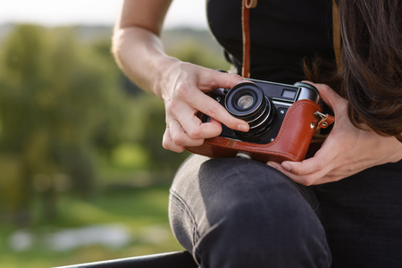 Young girl, the photographer adjusts the aperture on the camera before shooting the autumn landscapeの写真素材