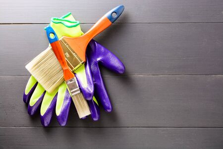 Pair of gloves with a brush on grey wooden background with copy space. Flat lay. Top viewの写真素材