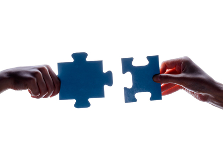 Silhouette of two hand holding couple of blue jigsaw puzzle piece on white background. concept - connection idea, sign, symbol, friendship, decision, success.の写真素材