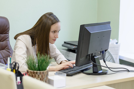 Young business woman working hard over the Desk in the study, economist accountant financial reporting, verifies accuracy of documents. Severe mental work.の写真素材