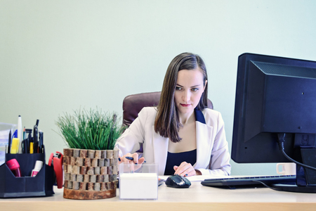 Young business woman working hard over the Desk in the study, economist accountant financial reporting, verifies accuracy of documents. Severe mental work.の写真素材