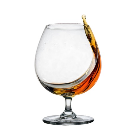 Glass wine glass with cognac and splash isolated on white backgroundの写真素材