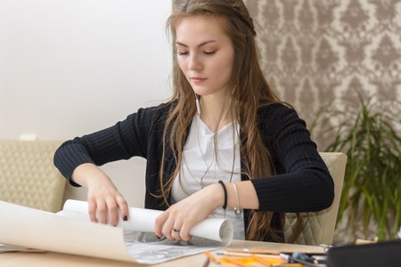 Frontal portrait of a young female student is engaged at the table draws sketches, sketches, plans, architecture. training and practice.の写真素材
