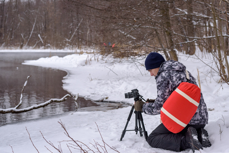 Woman Amateur photographer takes a winter landscape on the lake in the forest. copy space.の写真素材