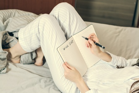 Cropped image of a woman in pajamas lying in bed and is a piece of desire. tonedの写真素材