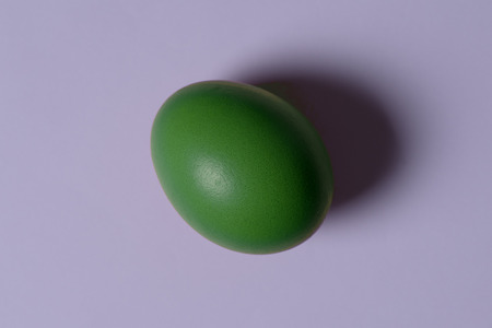 Minimalism. one green egg in the center image on a light ultraviolet backgroundの写真素材