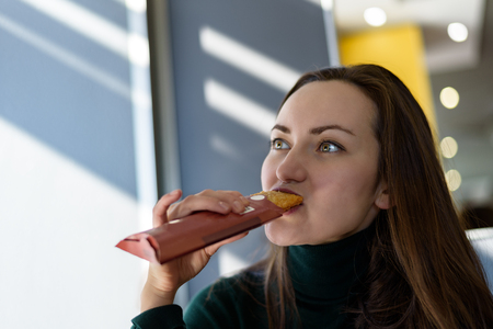 Young woman eating pie at the bistro at lunchtime.の写真素材