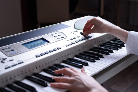 Female hands set up and play on an electronic piano, rear view.の写真素材