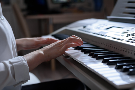 Close-up of female hands playing the synthesizer, shallow depth of field.の写真素材