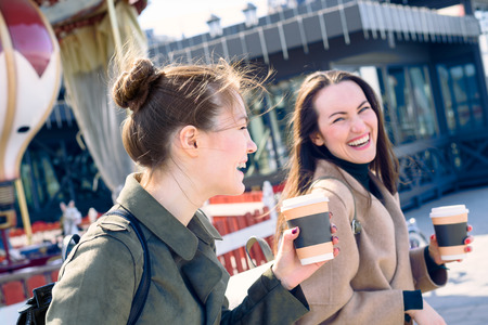 Happy two young women are smiling heavily and laughing walking the streets of the city on a Sunny...