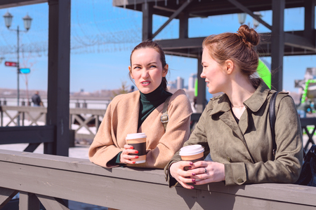 Conversation on a walk two girls with coffee in hand.の写真素材