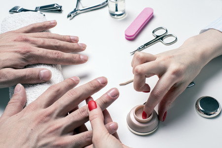 Men's manicure. woman beautician applies moisturizer to dry male hands.の写真素材