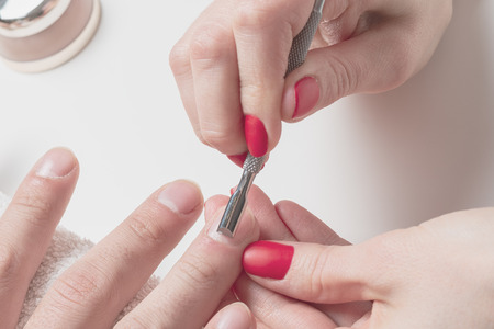 Men's manicure. hands of the beautician treated cuticle of male hands using pusher, scraper.の写真素材