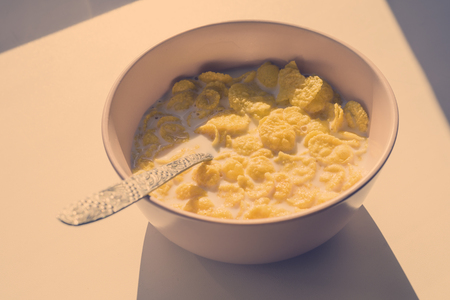 Cornflakes in a pink plate with a spoon for Breakfast, in the bright rays of the sun. toned.の写真素材