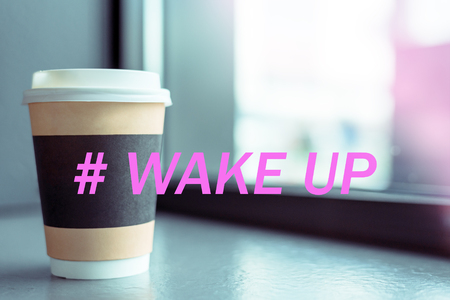 Paper Cup of the drink with a white plastic cap on the window of the coffee shop with the hashtag Wake up, the concept of a cheerful morning, charge, energy, Breakfast.の写真素材