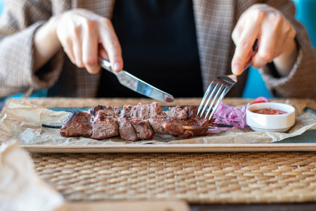 Close - up of women's hands with Cutlery in the restaurant cut barbecue.の写真素材