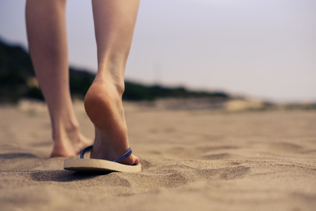 women's feet in the beach shale is on the sand close-up.