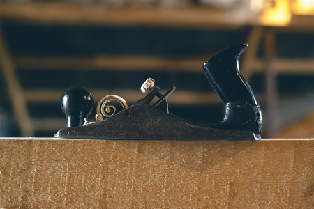 Vintage planer on wooden board close-up with a roll of shavings
