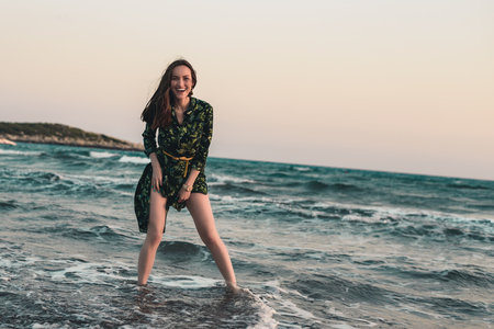Young woman having fun in the water on the beach at red sunset, smile, relax, entertainment.の写真素材