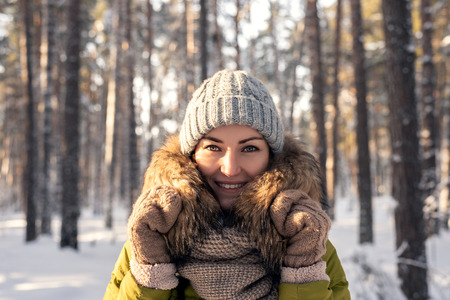 Horizontal winter portrait of a young woman on a coniferous forest background on a Sunny day. Girl...