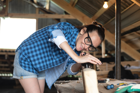 Woman in safety glasses working planer on wooden board front view.の写真素材