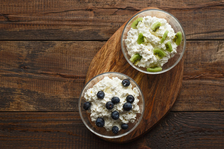 Top view cottage cheese blueberries and kiwis on a wooden stand with natural light with copy spaceの写真素材