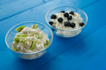 milk product, cottage cheese with berries and fruit in bowls on blue background. Healthy diet Breakfastの写真素材