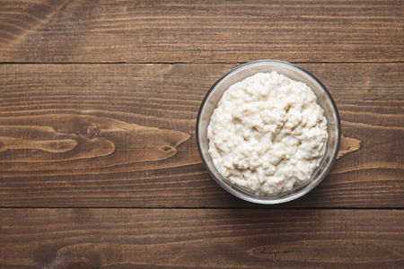 Minimalistic food background, oatmeal in a plate on a brown wooden table, copy space, top view, healthy Breakfastの写真素材