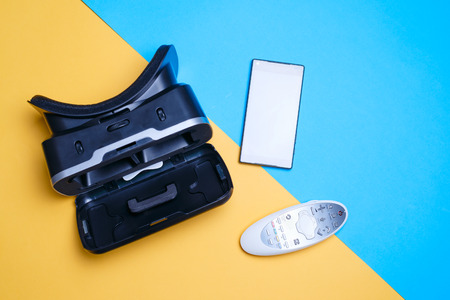 vr glasses, smartphone, remote on yellow-blue background. Duotone concept