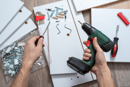 top view men's hands with tools with furniture elements on the floor. concept of furniture ssemblyの写真素材