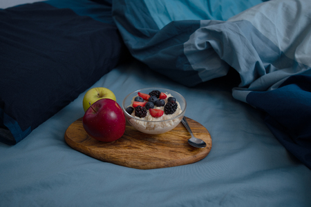Wooden tray on the bed with bowl of oatmeal and apples.の写真素材