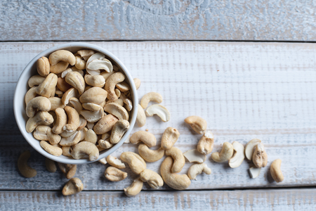 Top view of bowl with a handful of cashew nuts on wooden background.の写真素材