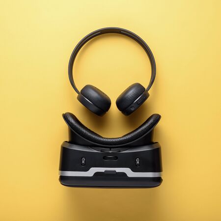 art design gadgets on yellow background, wireless headphones and VR glasses.の写真素材