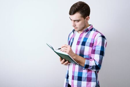 Young white man student studying lecture notes on gray background with copy space