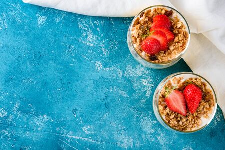 Flat Lay berry strawberry dessert with yogurt and muesli baked on red background with copy spaceの写真素材
